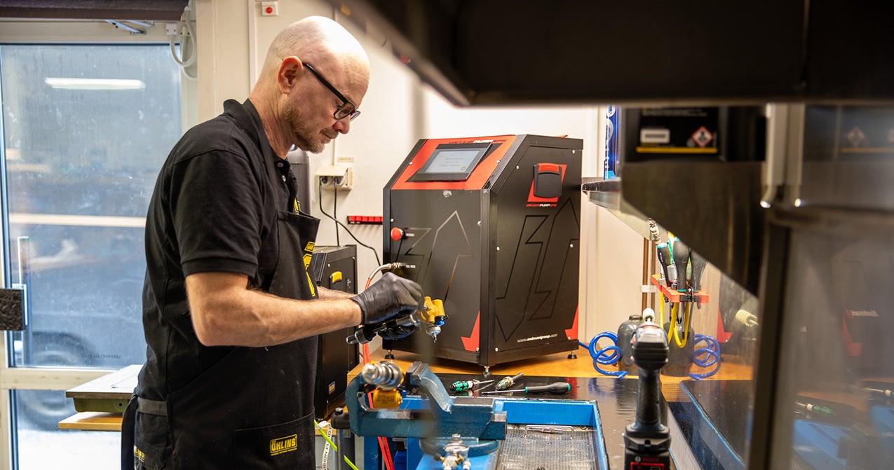 Service technician working on Öhlins suspension in the workshop.